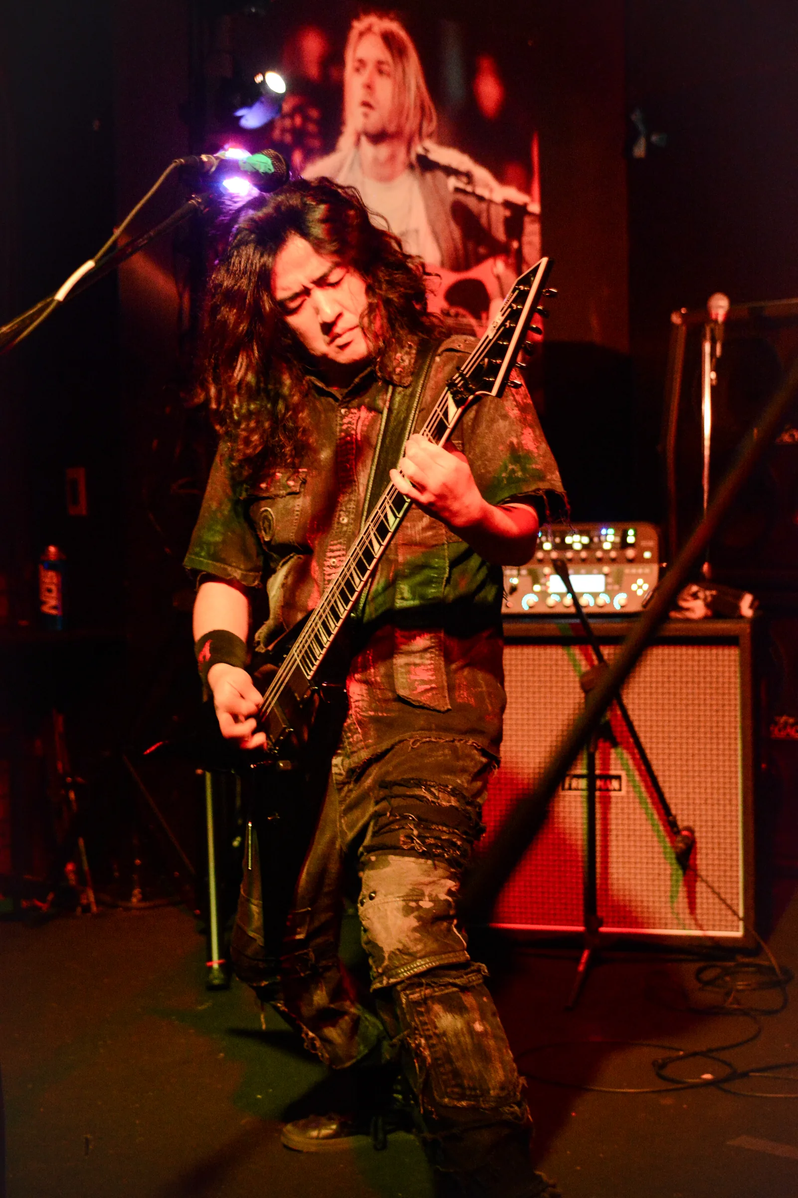 Masaki Murashita playing guitar onstage, with amplification behind him