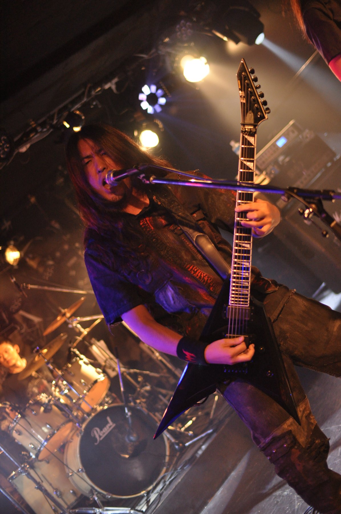 Masaki Murashita singing and playing guitar under stage lights