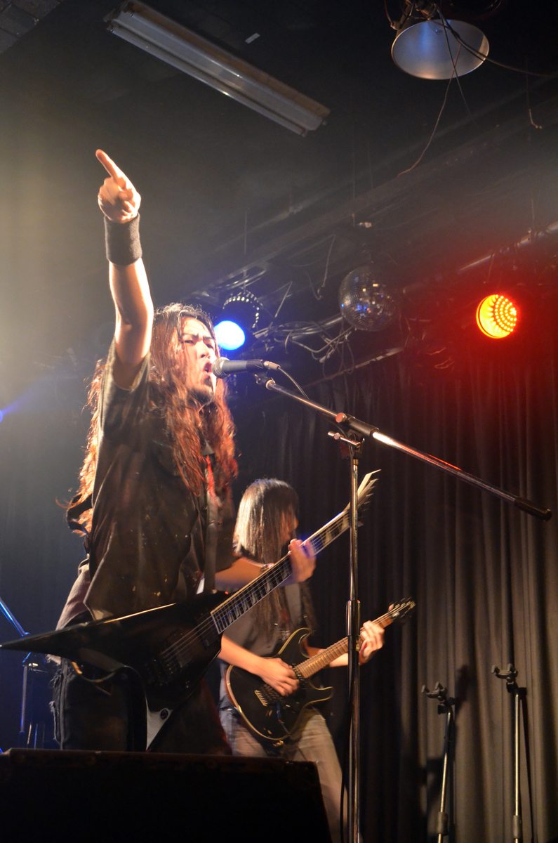 Masaki Murashita raising one arm during a live performance